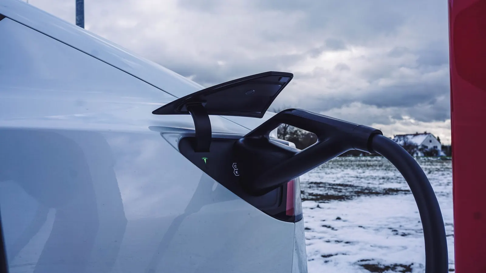 Elektrische auto aan de laadpaal in de sneeuw, met minder actieradius in de winter