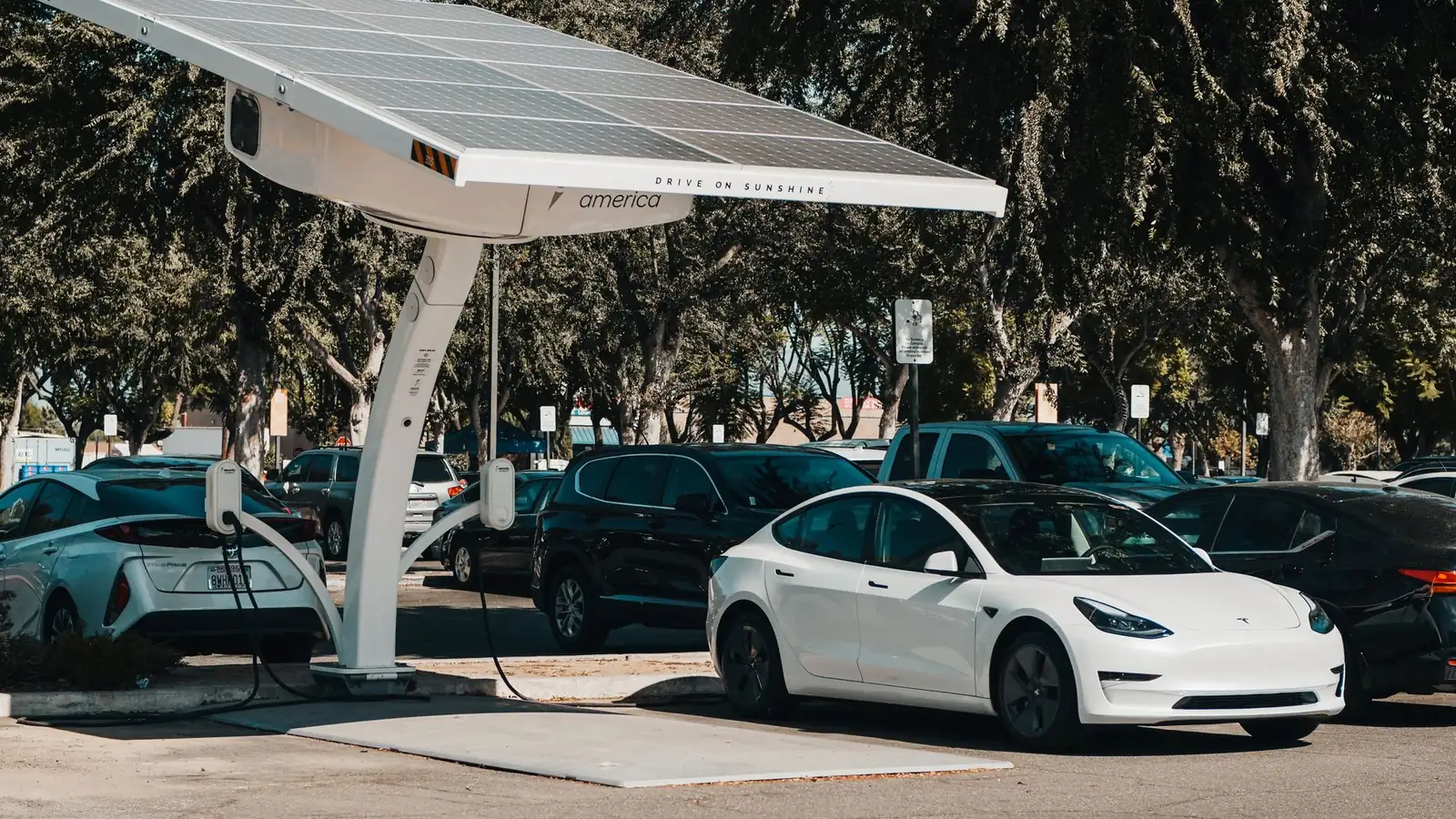 Elektrische auto aan een laadpaal bij een woning met zonnepanelen op het dak
